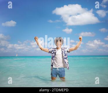 Ein überfröhlicher junger Mann in einem Sommerurlaub, der Glück mit den Armen im Meer gestreift hat Stockfoto