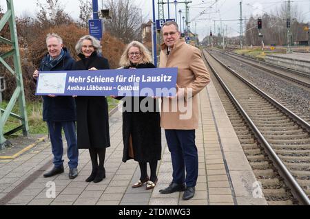 19. Dezember 2023, Brandenburg, Lübbenau: Alexander Kaczmarek (l-r), Gruppenbeauftragter der Deutschen Bahn für Brandenburg, Susanne Henckel, Staatssekretärin im Bundesverkehrsministerium, Ute Bonde, Geschäftsführer des VBB, und Rainer Genilke (CDU), brandenburgischer Minister für Infrastruktur und Raumordnung, stehen auf dem Bahnsteig des Bahnhofs Lübbenau während einer Presseveranstaltung zum Ausbau der Eisenbahnverbindung zwischen Lübbenau und Cottbus und halten ein Schild mit der Aufschrift „mehr Schiene für Lausitzer - Lübbenau - Cottbus-Erweiterung“. Foto: Soeren Stache/dpa Stockfoto