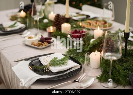 Teller mit Tannenzweig auf festlichem weihnachtstisch, komplett für die Feier vorbereitet Stockfoto