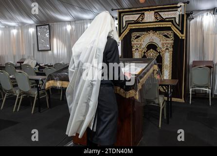 Ein anonymer orthodoxer jüdischer Mann, der einen tallis trägt, betet allein im Bimah in einer Synagoge im Rockland County, New York. Stockfoto