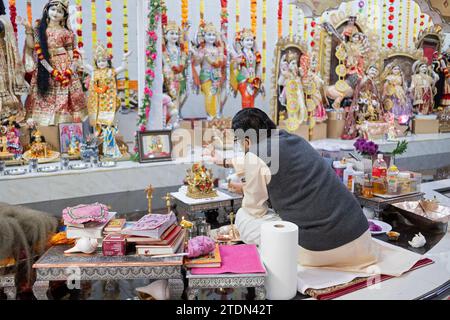 Ein hinduistischer Priester setzt eine Bindi auf eine kleine Statue von Ganesh am Geeta Hindu Tempel in der Corona, Queens, New York City. Stockfoto