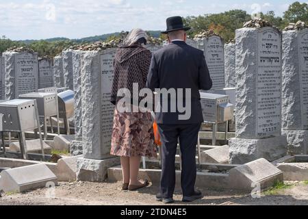 Ein chassidisches Paar betet am Grabstein eines Familienmitglieds auf dem Old Satmar Cemetery in Kiryas Joel in Monroe, New York. Stockfoto