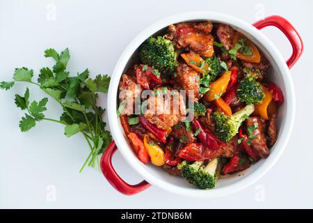 Gedünstetes Hähnchenfilet mit Gemüse in einer Pfanne, weißer Hintergrund, Draufsicht. Stockfoto