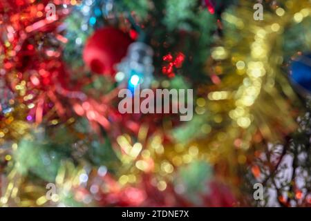 Defokussierte Nahaufnahme eines beleuchteten und dekorierten Weihnachtsbaums, die eine abstrakte Illustration mit Bokeh-Effekt und einem Gefühl von Wärme und Freude schafft. Stockfoto