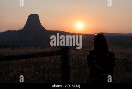 Silhouette einer jungen Dame, die einen Sonnenuntergang am Devil Tower in Wyoming beobachtet. Stockfoto