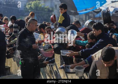 Rafah, Palästinensische Gebiete. Dezember 2023. Palästinenser sammeln sich mit Töpfen, um an einer Spendenstelle, die von einer gemeinnützigen Organisation in Rafah im südlichen Gazastreifen bereitgestellt wird, Lebensmittel zu erhalten. Quelle: Mohammed Talatene/dpa/Alamy Live News Stockfoto