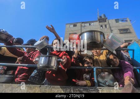 Rafah, Palästinensische Gebiete. Dezember 2023. Palästinenser sammeln sich mit Töpfen, um an einer Spendenstelle, die von einer gemeinnützigen Organisation in Rafah im südlichen Gazastreifen bereitgestellt wird, Lebensmittel zu erhalten. Quelle: Mohammed Talatene/dpa/Alamy Live News Stockfoto