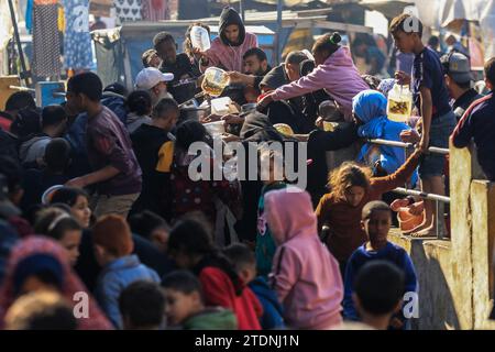 Rafah, Palästinensische Gebiete. Dezember 2023. Palästinenser sammeln sich mit Töpfen, um an einer Spendenstelle, die von einer gemeinnützigen Organisation in Rafah im südlichen Gazastreifen bereitgestellt wird, Lebensmittel zu erhalten. Quelle: Mohammed Talatene/dpa/Alamy Live News Stockfoto