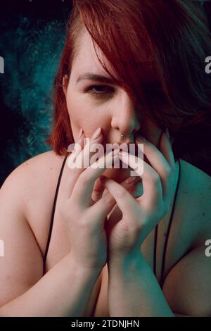 Vertikales künstlerisches Porträt für soziale Netzwerke, von großer Größe junge Latina Frau mit rotem Haar und weißem Haar, mit natürlichem Make-up, posiert sie Looki Stockfoto