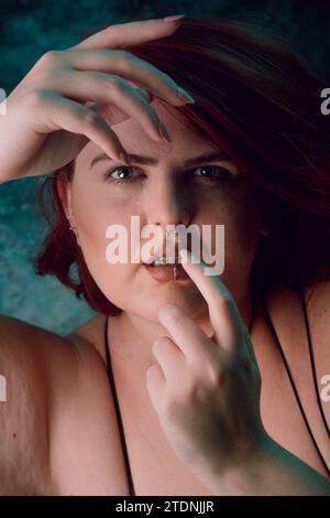 Vertikales künstlerisches Porträt für soziale Netzwerke, von großer Größe junge Latina Frau mit rotem Haar und weißem Haar, mit natürlichem Make-up, posiert sie Looki Stockfoto