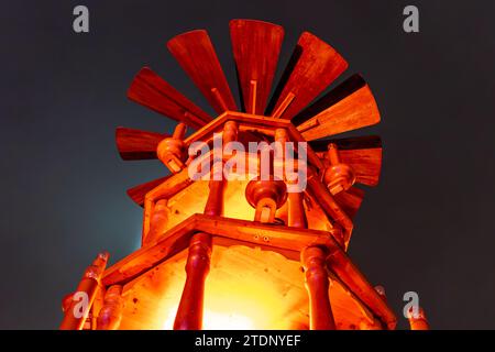 Eine traditionelle Holzwindmühle oder ein Turm, an einem Wurststand auf einem deutschen Weihnachtsmarkt in Berlin bei Nacht. Stockfoto