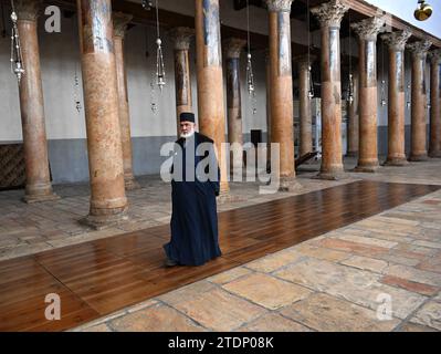 Bethlehem, Westjordanland. Dezember 2023. Ein Priester spaziert am Montag, dem 18. Dezember 2023 in der biblischen Stadt Bethlehem, West Bank, in der Geburtskirche Jesu, die als Ort der Geburt Jesu gilt. Die Kirche, die normalerweise mit Touristen gefüllt ist, ist seit dem 8. Oktober leer, dem Tag, nachdem die Hamas Israel angegriffen hatte und der Krieg im Gazastreifen begann. Christliche Führer haben die Errichtung des Weihnachtsbaums auf dem Managerplatz, fröhliche Straßendekorationen und Feierlichkeiten in Solidarität mit den Palästinensern in Gaza abgesagt. Foto: Debbie Hill/ Credit: UPI/Alamy Live News Stockfoto