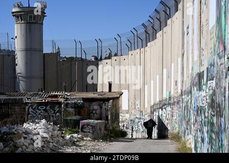 Bethlehem, Westjordanland. Dezember 2023. Ein Palästinenser geht am Montag, 18. Dezember 2023, in der biblischen Stadt Bethlehem, Westjordanland, an der israelischen Trennmauer entlang. Bethlehem ist normalerweise voller Touristen, ist aber seit dem 8. Oktober leer, dem Tag nach dem Angriff der Hamas auf Israel und dem Beginn des Krieges im Gazastreifen. Christliche Führer haben die Errichtung des Weihnachtsbaums auf dem Managerplatz, fröhliche Straßendekorationen und Feierlichkeiten in Solidarität mit den Palästinensern in Gaza abgesagt. Foto: Debbie Hill/ Credit: UPI/Alamy Live News Stockfoto