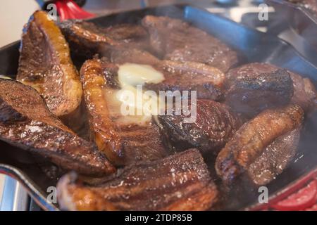 Barbecue picanha mit Butter geröstet. Mehrere Steaks in der Pfanne aus nächster Nähe gesehen. Brasilianisches Barbecue. Stockfoto