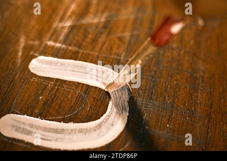 Lackierte Holzoberfläche mit Pinsel und weißer Farbe. Natürliche Holzstruktur. Stockfoto