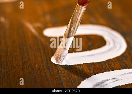 Lackierte Holzoberfläche mit Pinsel und weißer Farbe. Natürliche Holzstruktur. Stockfoto