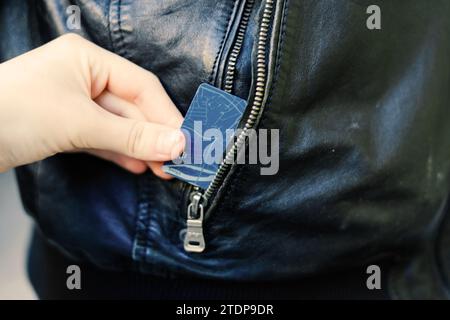 Die Hand zieht Papiergeld und Karte aus der Tasche. Ein Dieb hat einen Mann ausgeraubt. Bargelddiebstahl, kriminelles Konzept. Stockfoto