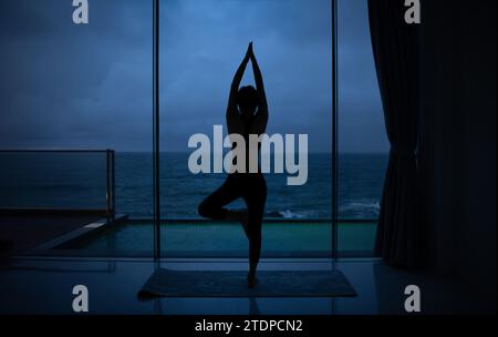 Die schöne Frau sieht am Strand und macht Yoga-Posen Stockfoto