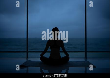 Die schöne Frau sieht am Strand und macht Yoga-Posen Stockfoto