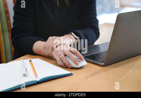 Eine Frau, die mit einem Laptop und einer Maus am Schreibtisch arbeitet, klagt über Schmerzen im Handgelenk Stockfoto