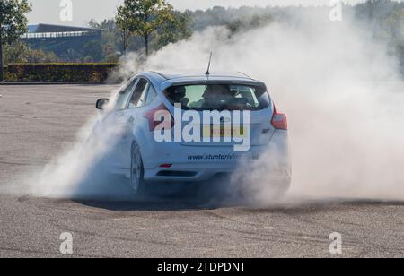 Stuntfahrer Paul Swift fährt seinen Ford Focus auf zwei Rädern und Mustang dreht sich Stockfoto