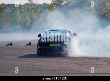 Stuntfahrer Paul Swift fährt seinen Ford Focus auf zwei Rädern und Mustang dreht sich Stockfoto