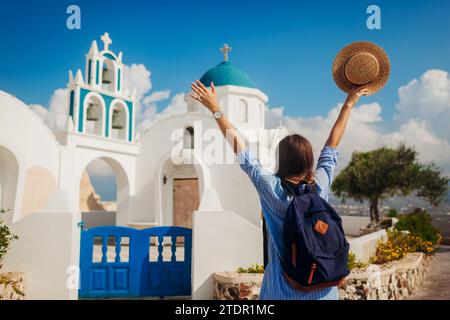 Inselreisender Santorini erkundet die griechische Kirchenarchitektur in Akrotiri. Glückliche Frau, Touristen-Backpacker, genießt die Landschaft. Reisen durch Europa Stockfoto