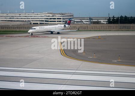 Flugzeug N390CA ein Mitsubishi CRJ-701ER Passagierflugzeug auf dem Asphalt am Detroit Metropolitan Wayne County Airport mit der Parkstruktur i Stockfoto