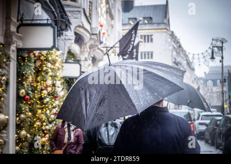 Regnerische Londoner Straßenszene mit Sonnenschirm und Geschäften Stockfoto