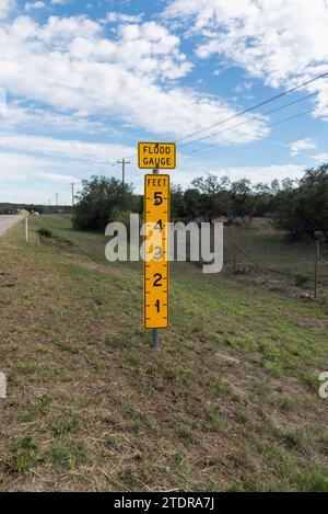 Gelbes Zeichen in Form eines Lineals, ein Flutmesser am Rande einer Autobahn in Texas, USA. Stockfoto