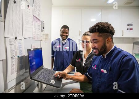 Krankenschwester Evans Sarbeng im Behandlungsraum mit Klinikleitung Dani Botelho und Mitschwester John Haizel Cobbinah. Sowohl Evans als auch John sind Krankenschwestern aus Ghana, während Dani aus Portugal kommt. St. Cecilias Pflegeheim Scarborough. Stockfoto