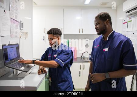 Krankenschwester Evans Sarbeng im Behandlungsraum mit Mitschwester John Haizel Cobbinah. Sowohl Evans als auch John sind Krankenschwestern aus Ghana, während Dani aus Portugal kommt. St. Cecilias Pflegeheim Scarborough. Stockfoto