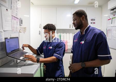 Krankenschwester Evans Sarbeng im Behandlungsraum mit Mitschwester John Haizel Cobbinah. Sowohl Evans als auch John sind Krankenschwestern aus Ghana, während Dani aus Portugal kommt. St. Cecilias Pflegeheim Scarborough. Stockfoto