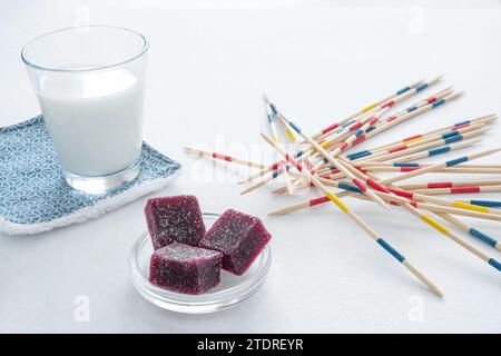 Fruchtpasten und ein Glas Milch vor einem Brettspiel für einen entspannenden Moment für Kinder Stockfoto