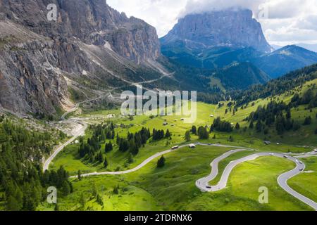 Luftdrohnenaufnahme von malerischen Bergrücken und Gipfeln der Dolomiten. Passo Gardena Grüne Hügel mit geschwungener bergiger Straße mit Autos, die durch Kurven fahren Stockfoto