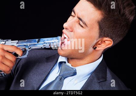 Betonte jungen Geschäftsmann mit einer Pistole auf den Kopf (isoliert auf schwarz) Stockfoto