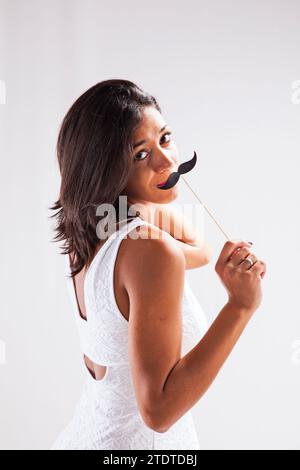 Eine junge Frau holst einen Schnurrbart aus Papier Stockfoto