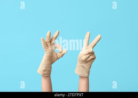 Hände in warmen Handschuhen mit Gesten auf blauem Hintergrund Stockfoto