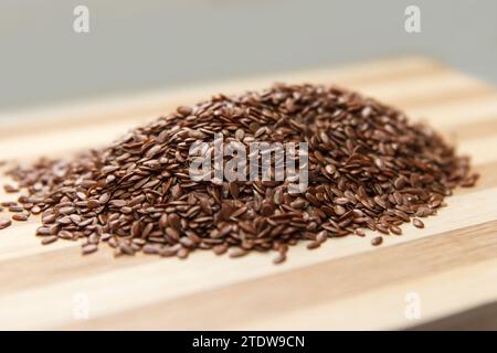 Viele rohe Leinensamen liegen auf einer Holzfläche in der Küche. Seitenansicht. Fokus in der Mitte der Seeds Stockfoto