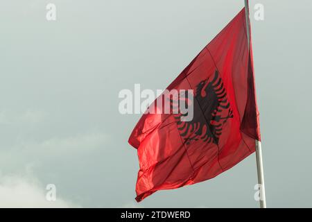 Große albanische Flagge flattert im Wind vor einem klaren blauen Himmel und symbolisiert nationalen Stolz und Erbe Stockfoto