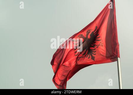 Große albanische Flagge flattert im Wind vor einem klaren blauen Himmel und symbolisiert nationalen Stolz und Erbe Stockfoto