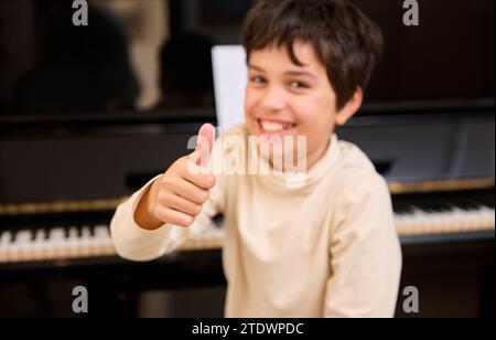 Details zu den Händen eines unscharf lächelnden Teenager, der den Daumen vor der Kamera zeigt, während er zu Hause Flügel spielt. Menschen. Bildung. Hobbys Stockfoto