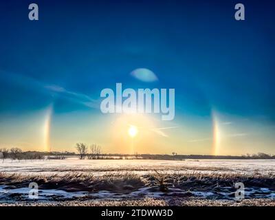 Atmosphärisches optisches Phänomen Sonnenhunde am Morgen über einem Schneefeld. Stockfoto