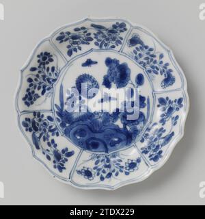 Untertasse mit Felsen, Blumensprays und Schmetterlingen, anonym, ca. 1700 - ca. 1724 Untertasse aus Porzellan mit geriffelter Wand und gewelltem Rand, in Unterlaze blau lackiert. Auf der Ebene ein Felsen mit zwei Blütenzweigen (Chrysantheme, Pfingstrose) und zwei Schmetterlingen; die Wand unterteilt sich in sechs Abteilungen mit Blumensträngen und Vögeln; drei Blumenzweige auf der Rückseite. Auf der Unterseite mit einer Dichtungsmarke in einem Doppelkreis gekennzeichnet. Blau Weiß. Porzellan. Glasur. Kobalt-(Mineral-)Malerei / Glasur Untertasse aus Porzellan mit geriffelter Wand und gewelltem Rand, in Unterlazeblaze blau lackiert. Auf der Ebene ein Stein Stockfoto