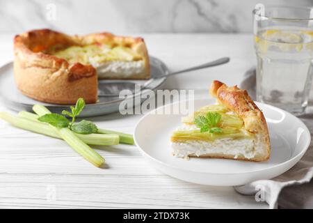 Frisch gebackener Rhabarberkuchen mit Frischkäse, Stielen und Minzblättern auf weißem Holztisch Stockfoto