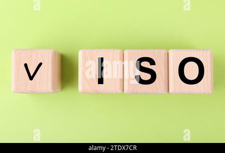 Internationale Organisation für Normung. Holzwürfel mit Häkchen und Abkürzung ISO auf hellgrünem Hintergrund, flache Lagen Stockfoto
