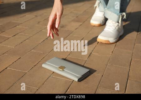 Frau, die draußen graue Handtasche aufnimmt, Nahaufnahme. Verloren und gefunden Stockfoto