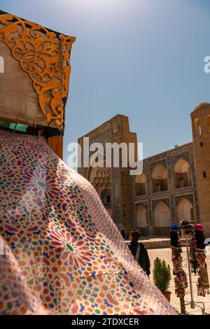 Schöne ethnische Stoffe, die mit dem Wind wehen, neben der alten Madrasah, Buchara, Usbekistan. Selektiver Fokus mit Kopierraum für Text Stockfoto