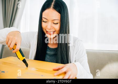 Eine Frau hält einen Universalschneider für präzises Auspacken und enthüllt Online-Shopping-Inhalte Stockfoto