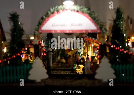 Coburg, Deutschland. Dezember 2023. Eine Miniatur-Dame kauft Spielzeug auf einem Weihnachtsmarkt. Rund 20 Meter vom Coburger Marktplatz entfernt, hat der ausgebildete Sozialarbeiter und jetzt Rentner Horst Gründel eine einzigartige, detailreiche Winterwelt geschaffen. In einem Raum in seiner Wohnung befindet sich ein kleiner Weihnachtsmarkt mit einer Größe von etwa acht Quadratmetern. Über 30 Stände, eine Modelleisenbahn, vier Krippen, eine Gondel, ein Karussell und vieles mehr beleben die Landschaft. Gründel begann in den 1970er Jahren mit dem Bau der ersten Verkaufsstände Quelle: Pia Bayer/dpa/Alamy Live News Stockfoto
